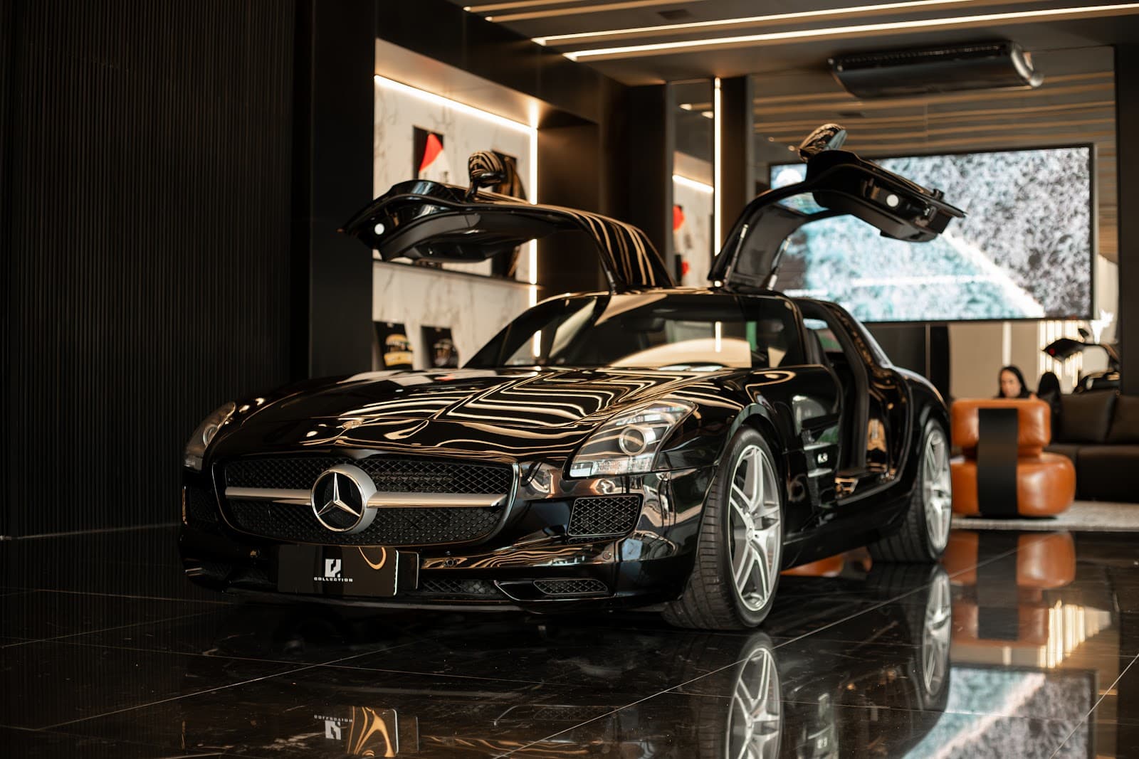 Showroom da Factory Boutique com um Mercedes preto de portas asa de gaivota abertas sobre o piso de mármore escuro