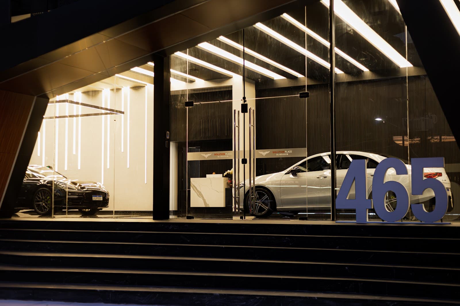 Entrada da Factory Boutique e o salão da fábrica da Solution Place, com carros em produção sob as luzes
