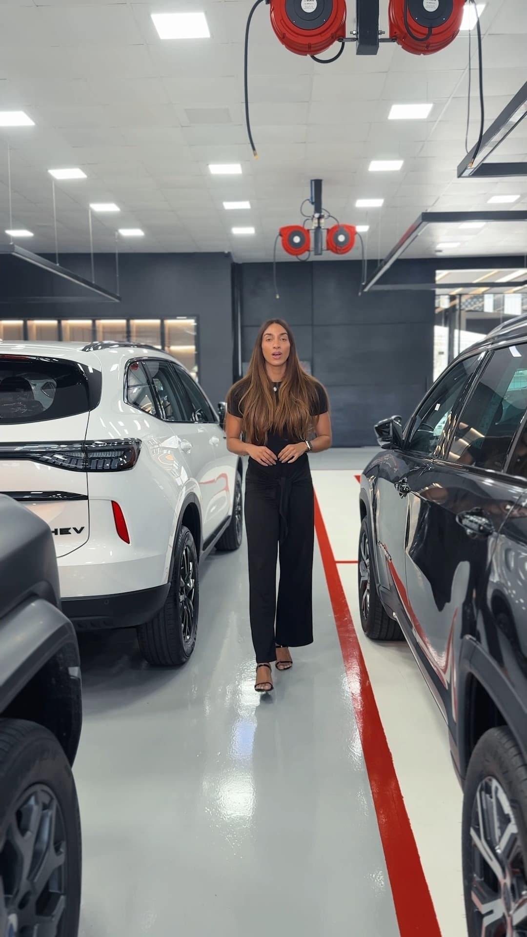 Consultora da Solution Place no showroom, entre um SUV branco e um carro preto prontos para entrega