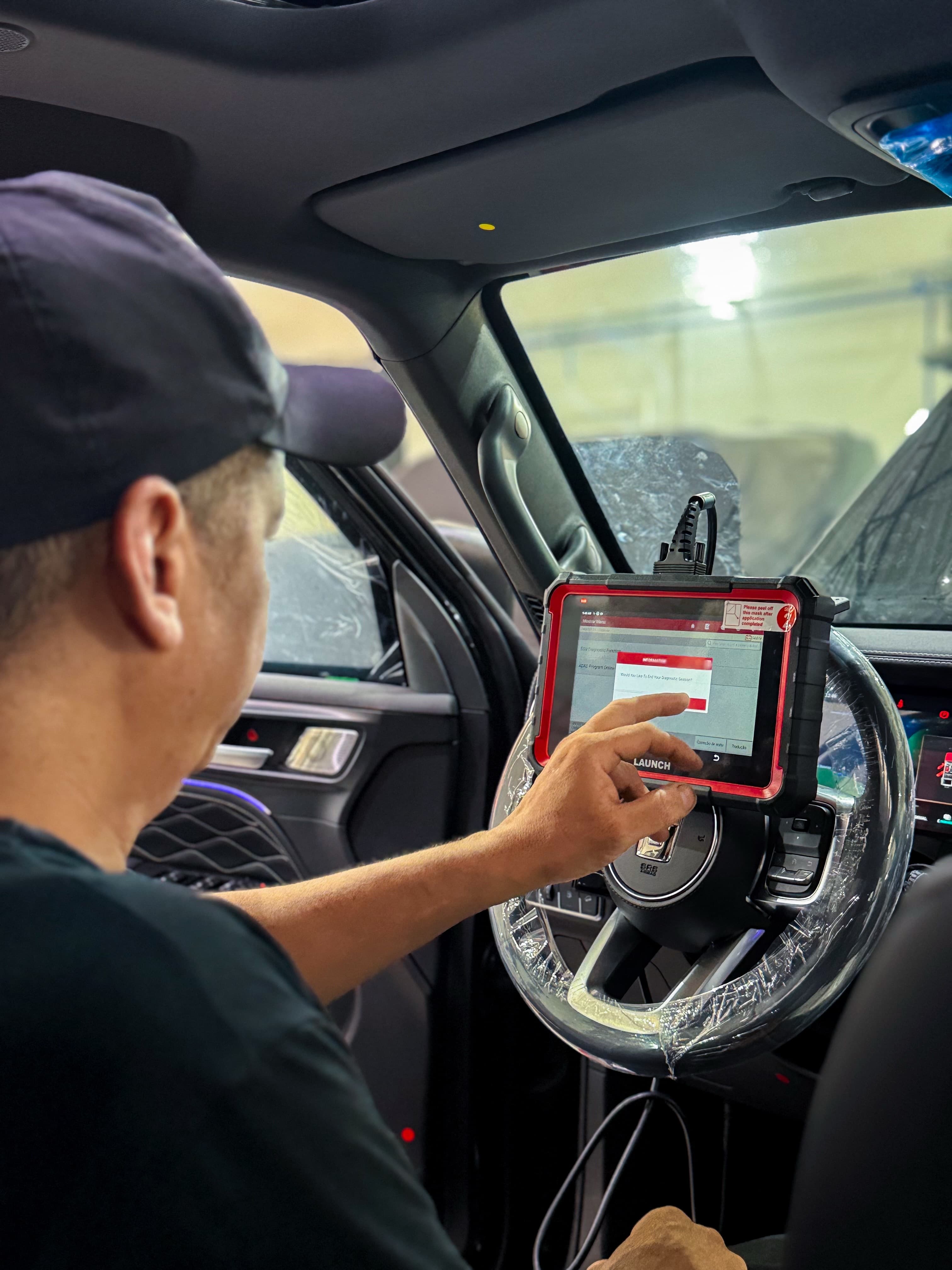 Técnico da Solution Place fazendo diagnóstico com tablet no volante de um carro blindado