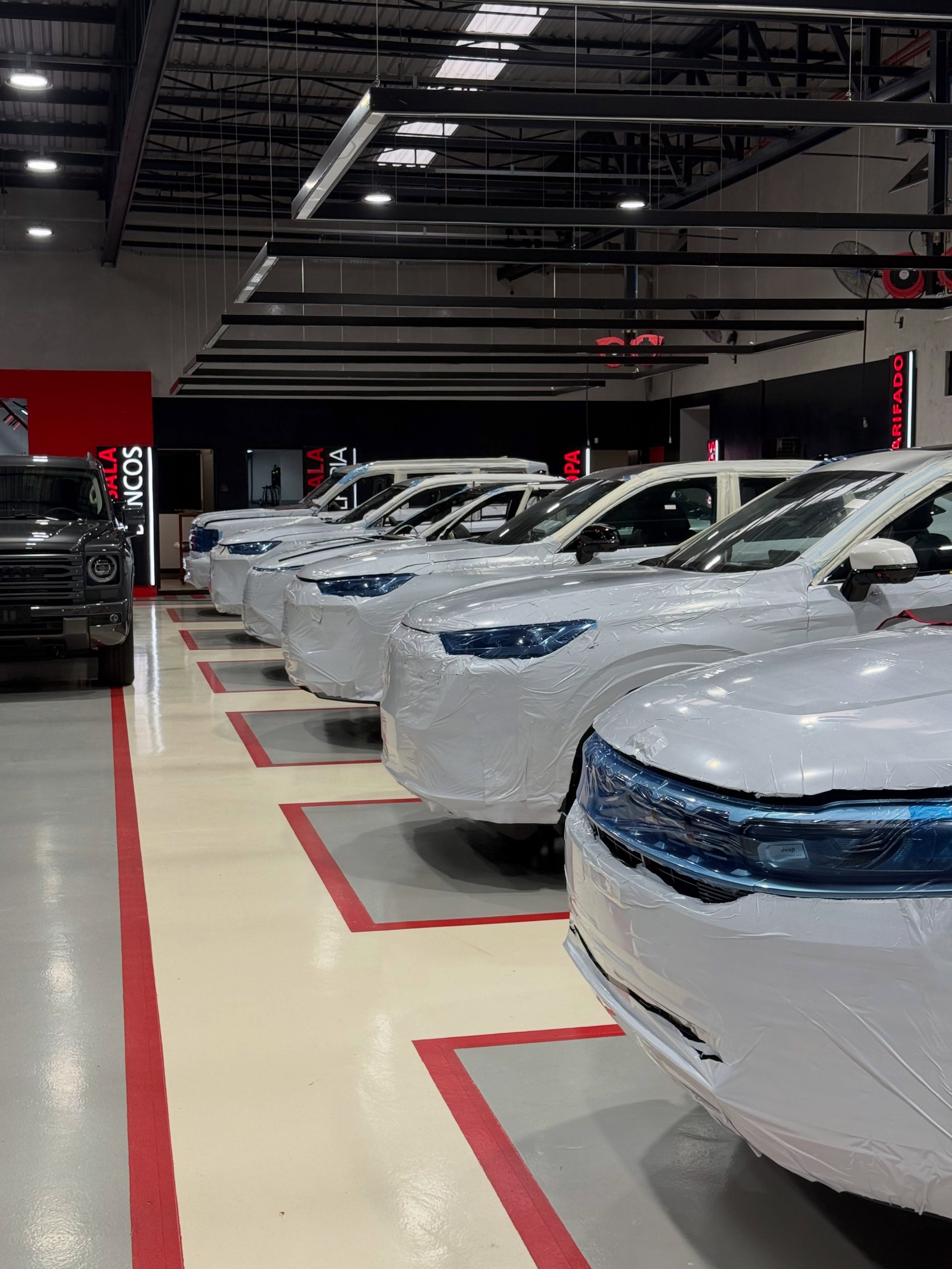 Linha de produção da Solution Place com carros brancos alinhados sobre o piso com faixas vermelhas
